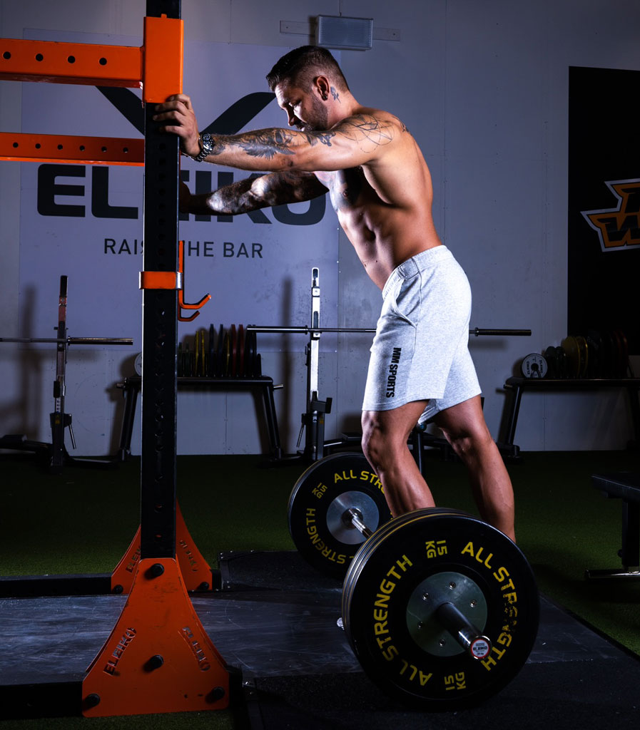 Coach is exercising in the gym, shirtless.
